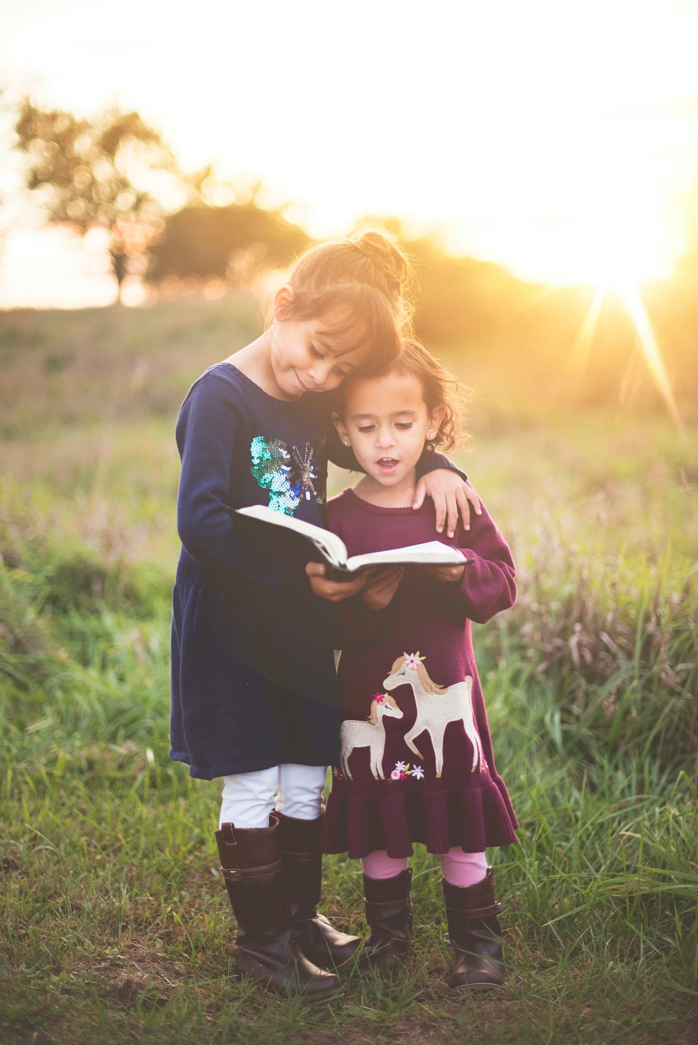Two children reading a storybook together in golden evening light